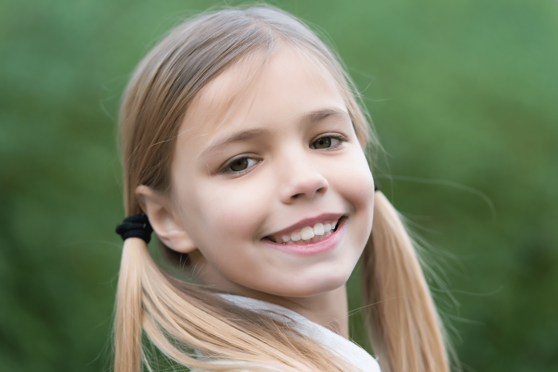 Smiling young girl showing her teeth outdoors